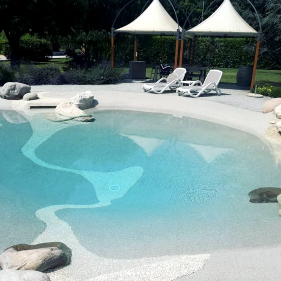 piscine naturelle avec plage, parasols et transats