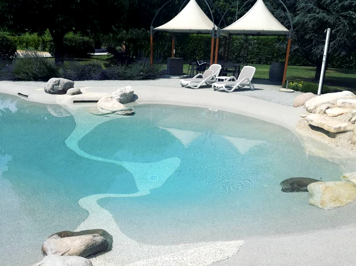 piscine naturelle avec plage, parasols et transats