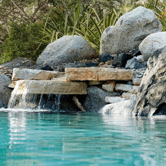 cascade de rochers naturels accolée à une piscine lagon